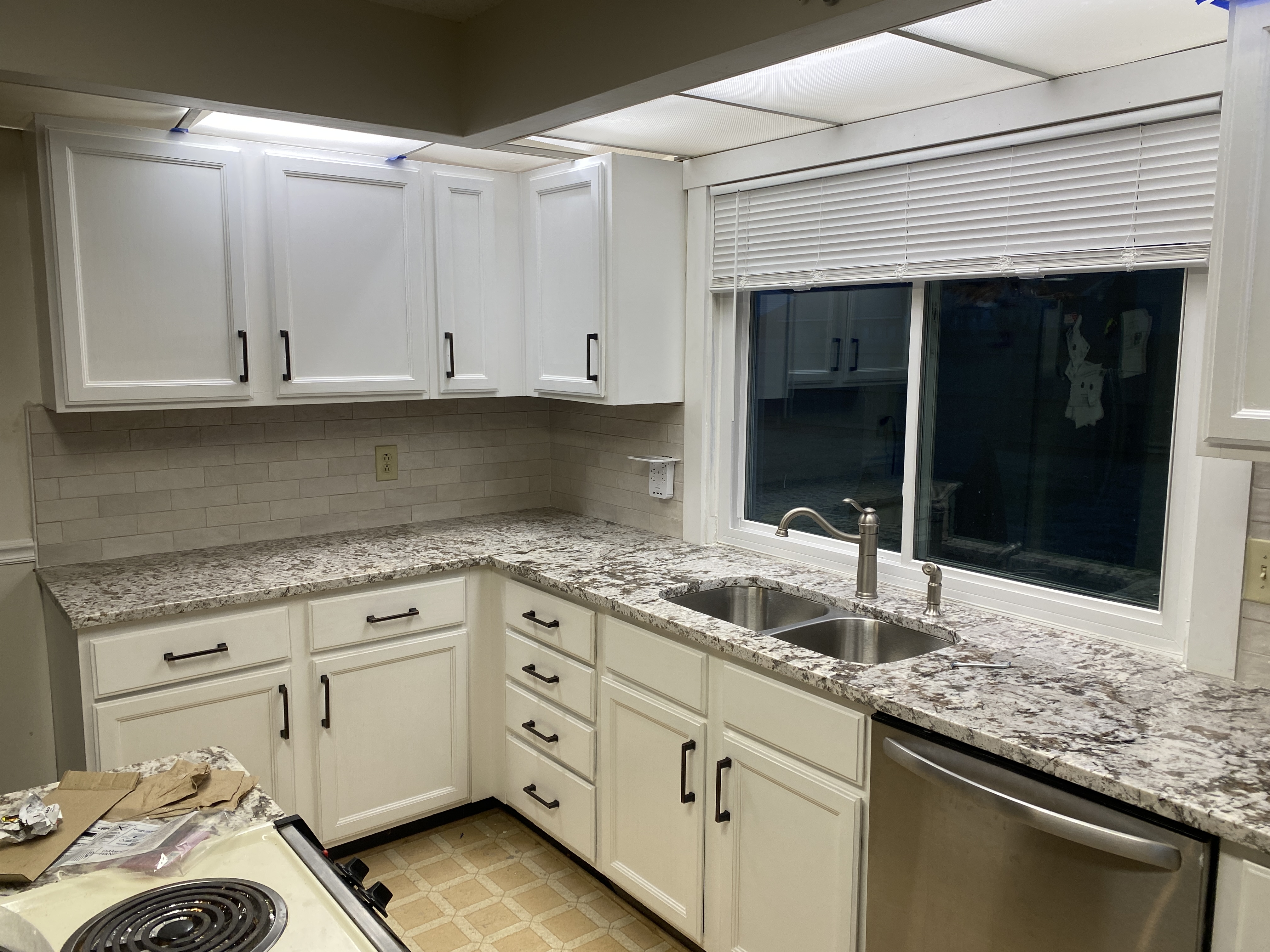 Kitchen remodel with white cabinets, subway tile backsplash, and granite counters